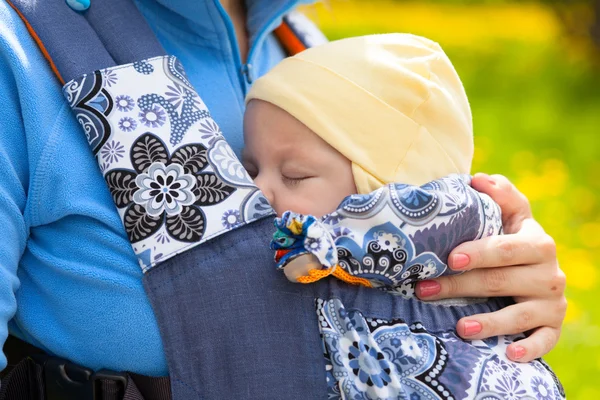 Newborn baby and mother outdoors walking with sling. — Stockfoto