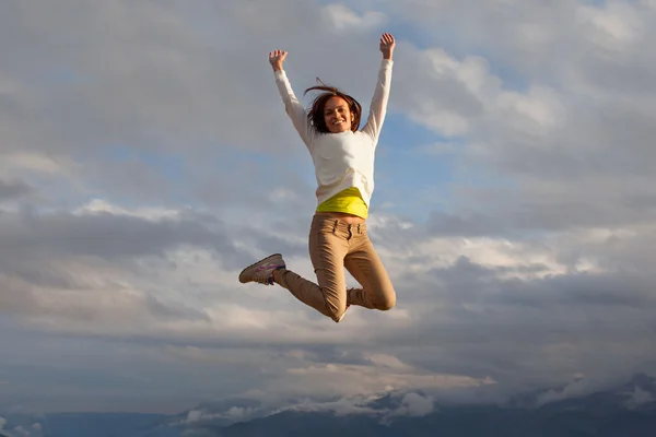 Jovem linda menina oa um pico de um salto de montanha — Fotografia de Stock