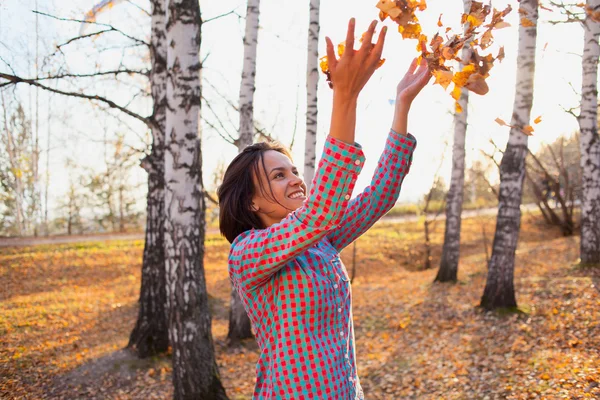 Ragazza nel parco autunnale giocare con le foglie — Foto Stock