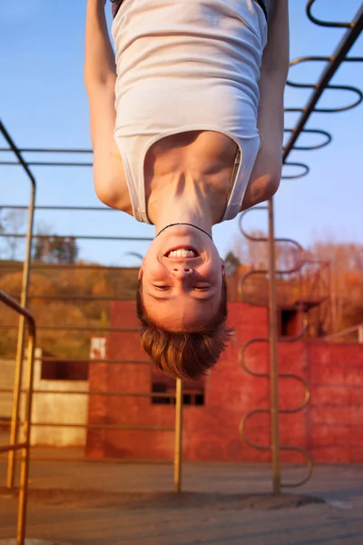 Menina pendurado de cabeça para baixo em anéis de ginástica — Fotografia de Stock