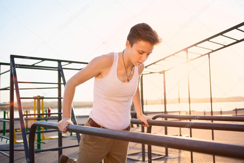 teen training on parallel bars outdoors