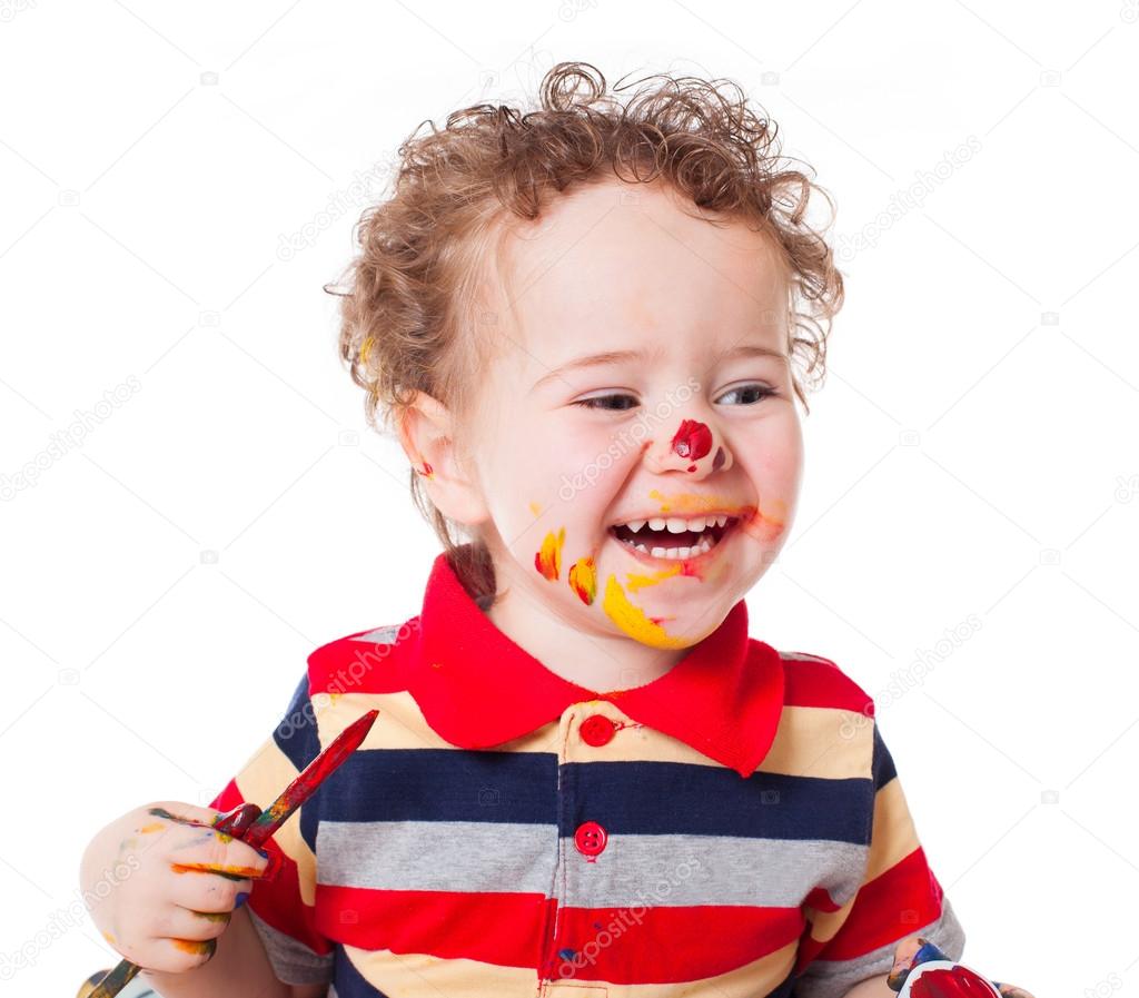 Cute happy baby boy playing with paints