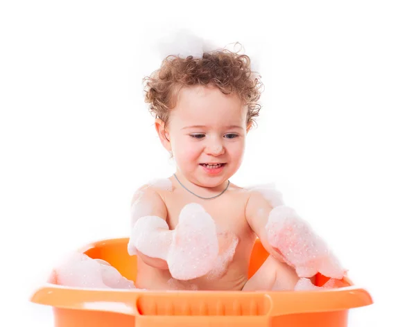 Cute happy baby playing with foam in bath