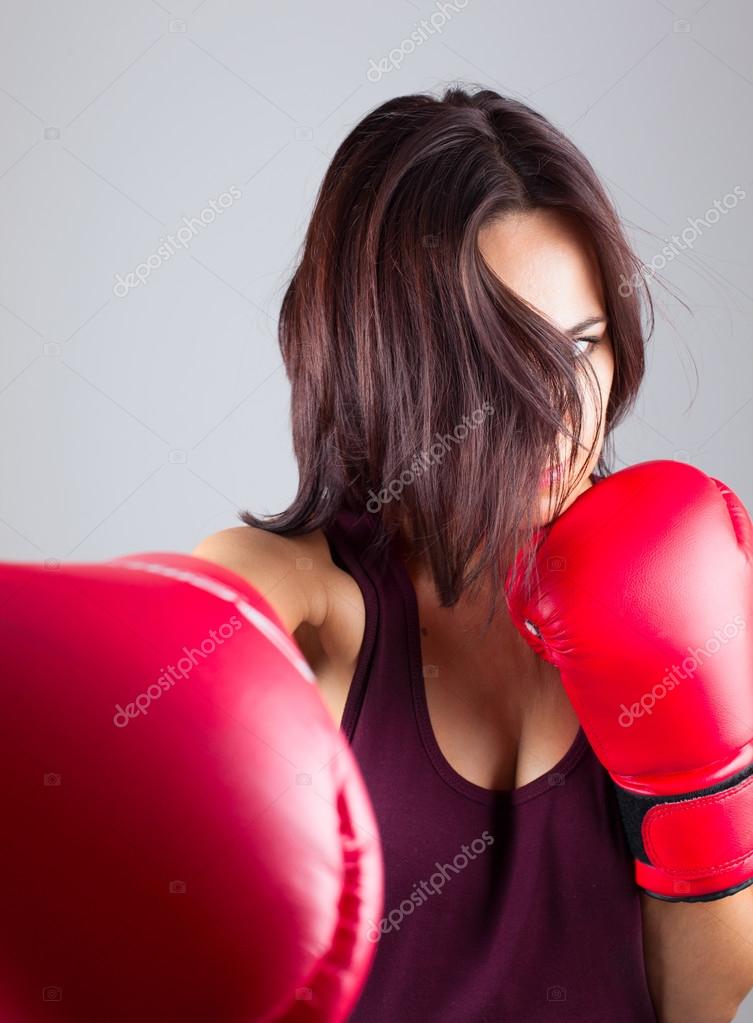 Deportiva mujer joven en guantes de boxeo rojos practicando golpes