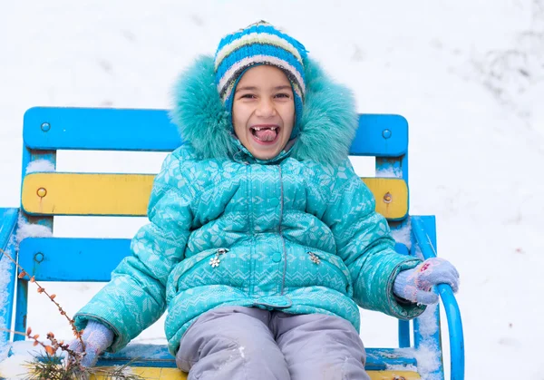 Happy kid girl child outdoors in winter sitting on bench — Stock Photo, Image