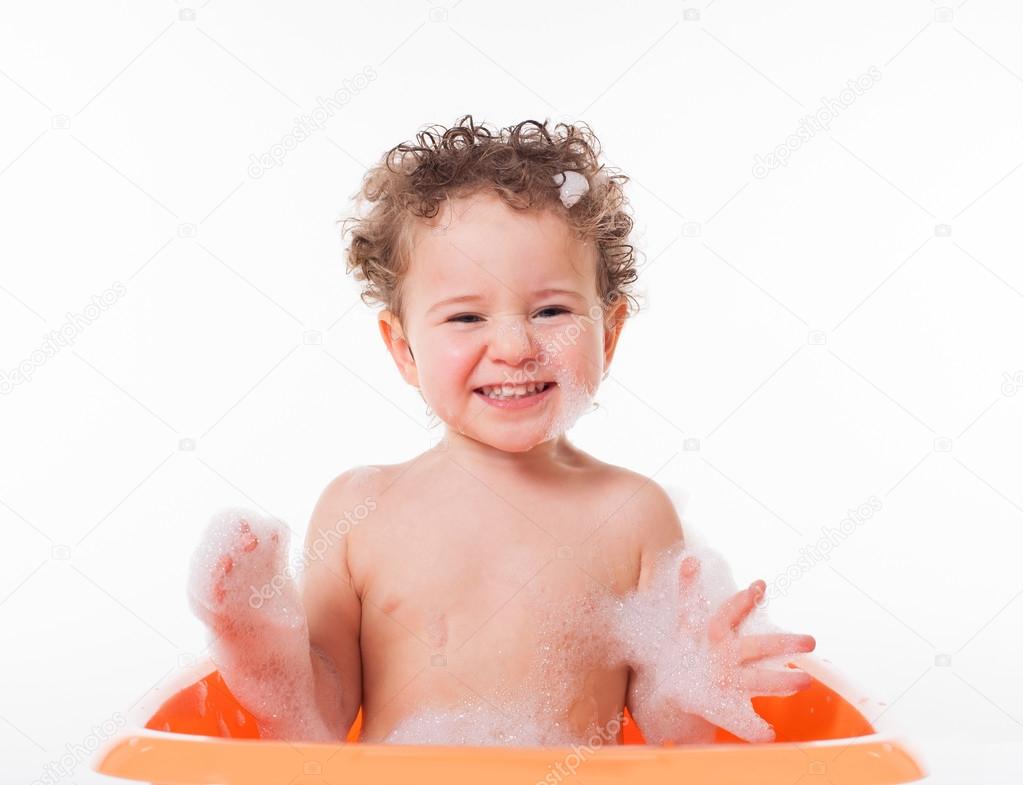 Cute happy baby playing with foam in bath