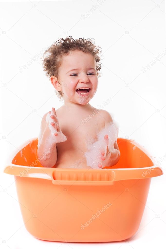 Cute happy baby playing with foam in bath