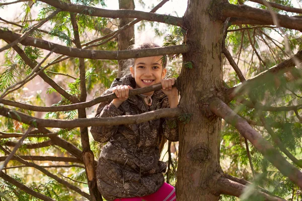 Fille enfant marche dans le parc se cachant parmi les branches d'arbre — Photo