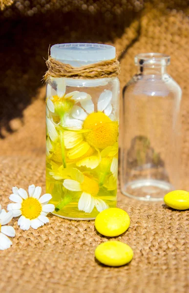 Ароматное масло ромашковых цветов в стеклянной бутылке макро на деревянный стол горизонтальный — стоковое фото