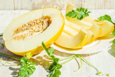 Beyaz ahşap zemin üzerinde sulu olgun sarı kavun.