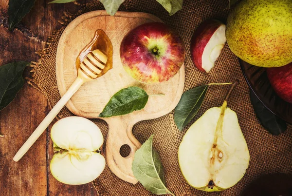 juicy, ripe apples and pear with honey on wooden background.