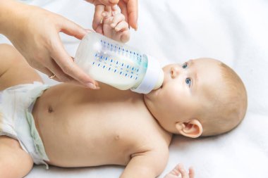 Anne bebeği bir şişeyle besliyor. Seçici odaklanma. İnsanlar.