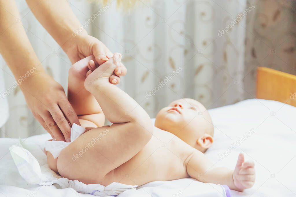 The mother changes the baby's diaper. Selective focus. People.