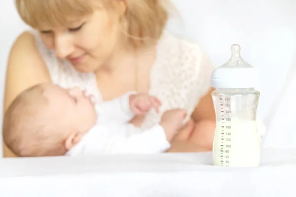 Mother feeds the baby from a bottle. Selective focus. People.