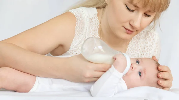 Mother feeds the baby from a bottle. Selective focus. People.