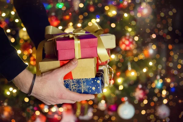 Christmas gifts in the hands of a man under the tree. Selective focus. Holiday.
