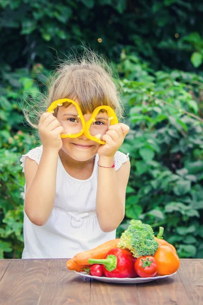 The child eats vegetables in summer. Selective focus. People.