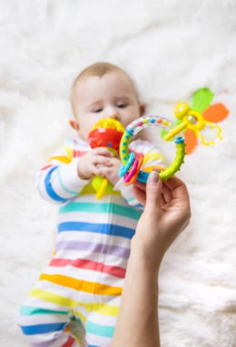 Anne bebeğe bir çıngırak verir. Seçici odaklanma. çocuk.