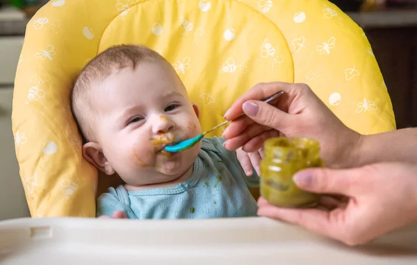 Little baby is eating broccoli vegetable puree. Selective focus. people. — Stock Image Little Baby Eating Broccoli Vegetable Puree Selective Focus People Royalty Free Stock Photos
