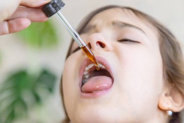 Anne çocuğuna damlatıcıyla vitamin damlası veriyor. Çocuklar için beslenme takviyeleri. Seçici odak.