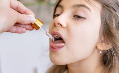 Anne çocuğuna damlatıcıyla vitamin damlası veriyor. Çocuklar için beslenme takviyeleri. Seçici odak.