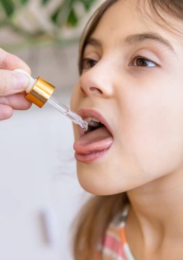 Anne çocuğuna damlatıcıyla vitamin damlası veriyor. Çocuklar için beslenme takviyeleri. Seçici odak.