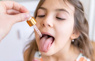 Anne çocuğuna damlatıcıyla vitamin damlası veriyor. Çocuklar için beslenme takviyeleri. Seçici odak.
