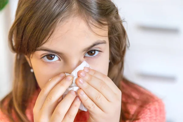 The child wipes a runny nose with a napkin. Selective focus. People.