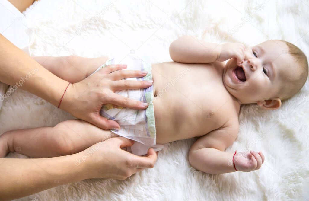 The mother is changing the baby's diaper. Selective focus. People.