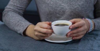 Masadaki kadın elinde bir fincan kahveyle. Seçici odaklanma. İç..