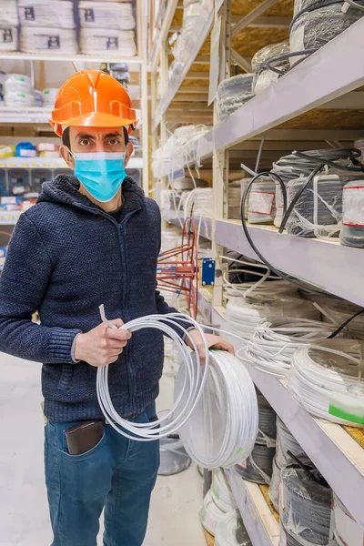 A man in a hardware store. Sells electrical cables. Selective focus. People.