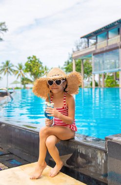 Havuzun yanında bir çocuk kokteyl içer. Seçici odak.