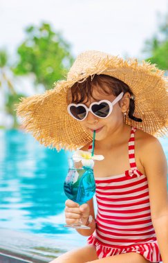 Havuzun yanında bir çocuk kokteyl içer. Seçici odak.