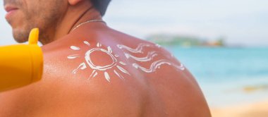 Sahilde sırtında güneş kremi olan bir adam. Seçici odaklanma. Seyahat.