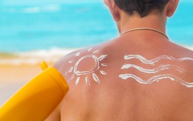 Sahilde sırtında güneş kremi olan bir adam. Seçici odaklanma. Seyahat.