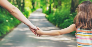 Anne ve çocuk el ele tutuşur. Seçici odaklanma. Doğa.