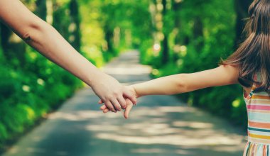 Anne ve çocuk el ele tutuşur. Seçici odaklanma. Doğa.