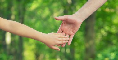 Baba ve çocuk el ele tutuşur. Seçici odaklanma. Doğa.