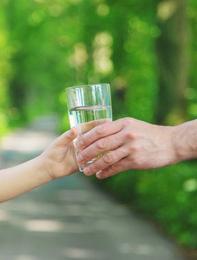 Baba çocuğa bir bardak taze su verir. Seçici odaklanma. Doğa.