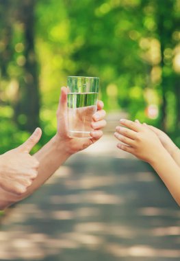 Baba çocuğa bir bardak taze su verir. Seçici odaklanma. Doğa.