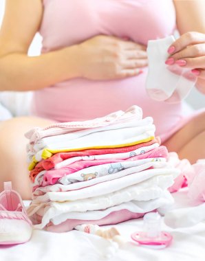 Hamile bir kadın bebek eşyaları katlıyor. Seçici odaklanma. insanlar.