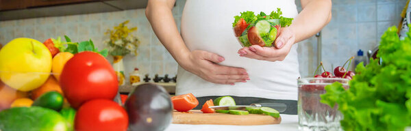 A pregnant woman eats vegetables and fruits. Selective focus. Food.