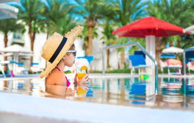 Çocuk havuz kenarında bir kokteyl içiyor. Seçici odaklanma. Çocuk.