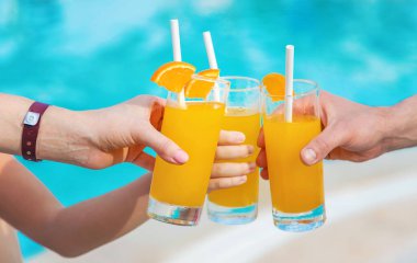 Havuz kenarındaki ailenin elinde kokteyl var. Seçici odaklanma. İnsanlar.