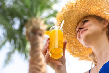 Palmiye ağacının altında kokteyl içen bir kadın. Seçici odaklanma. İnsanlar.