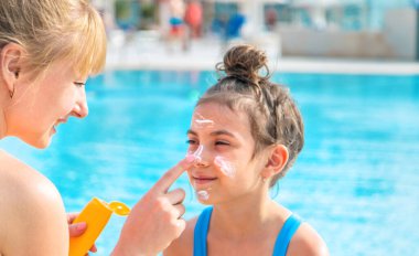Çocuk anneye güneş kremi sürüyor. Seçici odaklanma. Doğa.