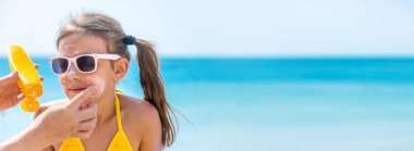 Çocuk anneye güneş kremi sürüyor. Seçici odaklanma. Doğa.