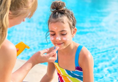Çocuk anneye güneş kremi sürüyor. Seçici odaklanma. Doğa.
