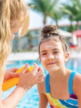 Çocuk anneye güneş kremi sürüyor. Seçici odaklanma. Doğa.