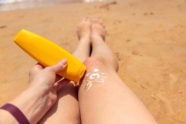 Bir kadın ayaklarını güneş kremiyle sarıyor. Seçici odaklanma. İnsanlar.